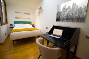 a bedroom with a bed and a desk with a laptop at Apartamentos Turísticos Pacios in Santiago de Compostela
