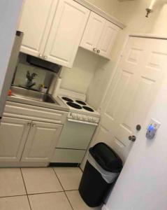 a white kitchen with a stove and a sink at Steps to the beach! in Miami Beach