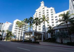 a large white building with palm trees in front of it at Steps to the beach! in Miami Beach