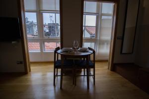 a table and chairs in a room with windows at Apartamentos Turísticos Pacios in Santiago de Compostela