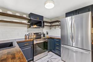 uma cozinha com armários azuis e um frigorífico de aço inoxidável em The Luxe/Hot Tub/12min to Horse Park/30 Min to Ark em Georgetown