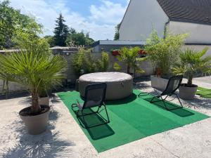 a patio with a table and chairs on a green rug at LE FAUBOURG SAINT MARTIN in Senlis