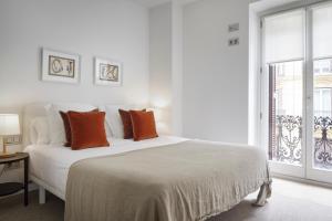 ein weißes Schlafzimmer mit einem großen Bett mit orangefarbenen Kissen in der Unterkunft Easo Suite 2B by FeelFree Rentals in San Sebastián