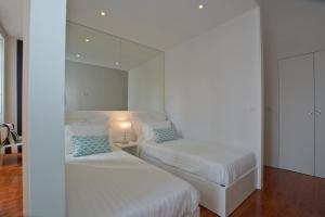 a white bedroom with two beds and a mirror at Bolhão Nobre Apartments in Porto