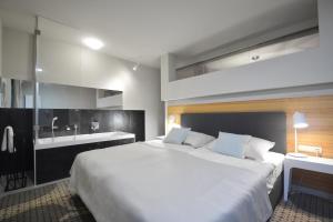 een slaapkamer met een groot wit bed en een wastafel bij Apartament Mare Baltico in Pogorzelica