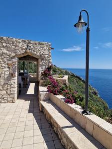 a stone building with a street light and the ocean at Oliventu - Tra gli ulivi sul mare in Leuca