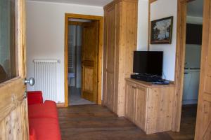 a living room with a tv and a red couch at Maison Carrel Elegant 7 in Breuil-Cervinia