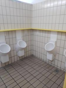 a bathroom with three urinals on a tiled wall at Munich Central Camping in Munich