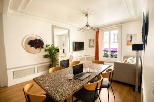 a dining room with a table with a laptop on it at Edgar Suites Martyrs - Lebas in Paris