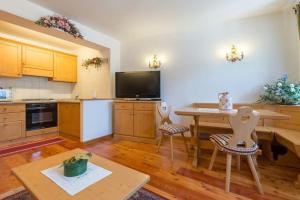 Il comprend une grande cuisine avec une table et une télévision. dans l'établissement Cozy apartment near Cortina, à San Vito di Cadore