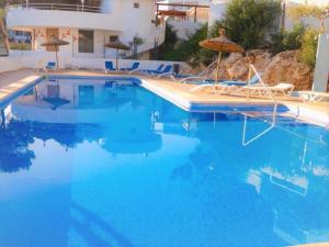 una gran piscina con agua azul y sombrillas en Playa d'Or 16 / Cala D'Or / Mallorca en Cala D'Or