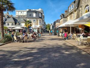 een groep mensen die aan tafels en stoelen op straat zitten bij Le Clos Tranquille in Saint-Cast-le-Guildo