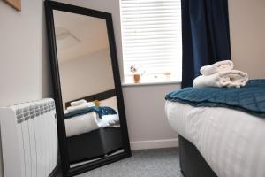 a bedroom with a mirror and a bed with towels at Harrogate Self Catering - Regent's Court Cherry Suite in Harrogate