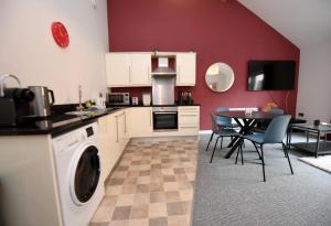 uma cozinha com armários brancos e uma mesa com cadeiras em Harrogate Self Catering - Regent's Court Cherry Suite em Harrogate