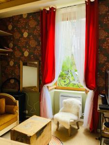 Zimmer mit roten Vorhängen, einem Stuhl und einem Fenster in der Unterkunft L’Hortense in Oloron-Sainte-Marie