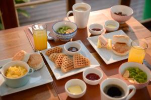 una mesa de madera con platos de desayuno y bebidas en Verde Madera Hostel B&B, en Santiago