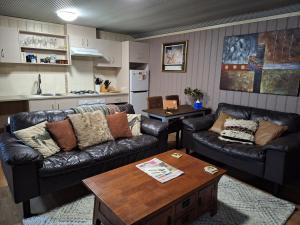a living room with two leather couches and a table at Little Para Cottage Tanunda in Tanunda
