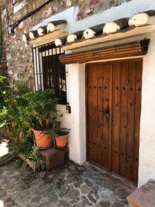 een huis met een houten deur en een aantal planten bij El Refugi in Vilafames