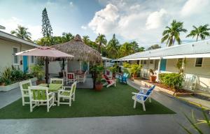 patio z krzesłami, stołami i parasolem w obiekcie Seashell Motel and International Hostel w mieście Key West