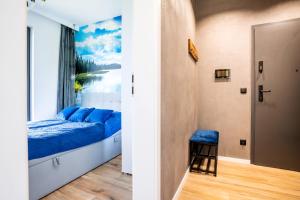 sypialnia z niebieskim łóżkiem i oknem w obiekcie Apartamenty Olimpijska z widokiem na jezioro w Olsztynie