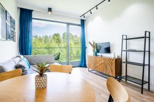 a living room with a table and a large window at Apartamenty Olimpijska z widokiem na jezioro in Olsztyn