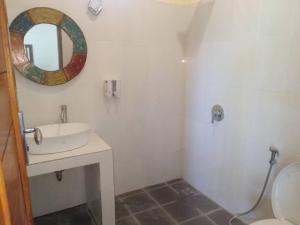 a white bathroom with a sink and a mirror at Pondok widji in Sukawati