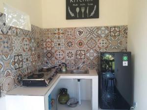a kitchen with a sink and a tile wall at Pondok widji in Sukawati