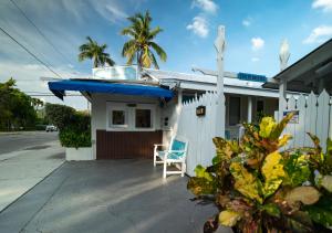 uma pequena casa com um guarda-chuva azul e uma cadeira em Seashell Motel and International Hostel em Key West