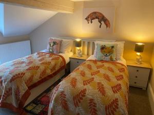 una camera con due letti e un orsetto di peluche sul cuscino di Happy Feet Cottage, Sleeps 6 a Bradwell