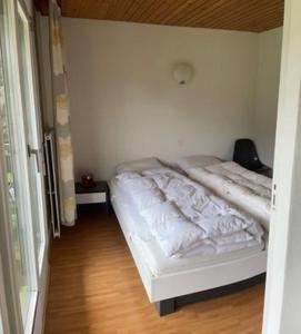 - un lit blanc dans une chambre dotée de parquet dans l'établissement Som Barnagn 7, à Savognin