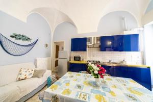 uma cozinha com armários azuis e uma mesa com um vaso de flores em La casa di Tina a 20 metri dal mare em Santo Stefano al Mare