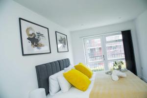 ein Schlafzimmer mit einem Bett mit gelben Kissen und einem Fenster in der Unterkunft Bridge Court by Sterling Edge Apartments - Luxury Aparthotel - Stylish 1-bed Apartments - Balcony with Canal View or Private Garden - Free Parking in Birmingham