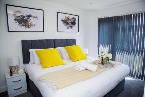 ein Schlafzimmer mit einem großen Bett mit gelben Kissen in der Unterkunft Bridge Court by Sterling Edge Apartments - Luxury Aparthotel - Stylish 1-bed Apartments - Balcony with Canal View or Private Garden - Free Parking in Birmingham