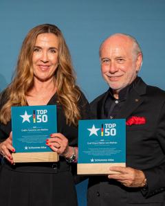 a man and a woman holding two awards at Relais & Châteaux Gut Steinbach Hotel Chalets SPA in Reit im Winkl