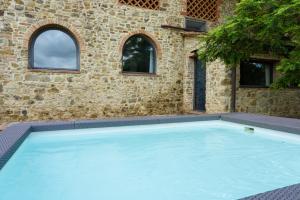 une grande piscine en face d'un bâtiment en briques dans l'établissement Villa Fienile Design, à SantʼAppiano