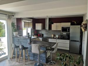 a kitchen with white cabinets and a counter with stools at Un instant avec vous in Saint-Martin-Boulogne