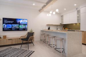 a kitchen with bar stools and a tv on the wall at Apartament Premium PINEA 205 in Pobierowo