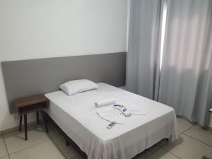 Una cama con sábanas blancas y un plato. en Achei Casa , aluguel por temporada en Porto Velho