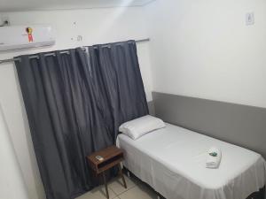 um pequeno quarto com uma cama e uma cortina em Achei Casa , aluguel por temporada em Porto Velho