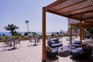 a patio with chairs and tables and a pergola at Atlantica Bay - Adults Only in Limassol