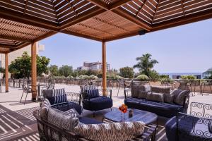 un patio con sofás, mesas y sillas en Atlantica Bay - Adults Only, en Limassol