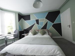 a bedroom with a large bed with a geometric wall at Grosvenor Suite in Royal Tunbridge Wells