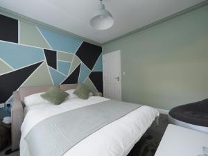 a bedroom with a white bed with a geometric wall at Grosvenor Suite in Royal Tunbridge Wells