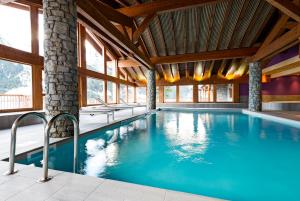 a swimming pool in a building with windows at Lagrange Vacances Les Hauts de la Vanoise in Pralognan-la-Vanoise