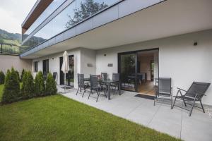 a patio with chairs and a table and a lawn at Thalhof Apartments in Brixen im Thale