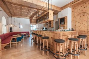 un bar in un ristorante con pareti e sgabelli in legno di Hotel Alpensonne - Panoramazimmer & Restaurant a Arosa