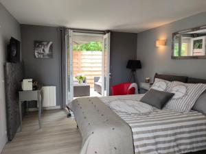a bedroom with a bed and a sliding glass door at Le Clos Fleuri proche de Bordeaux in Saint-Sulpice-et-Cameyrac