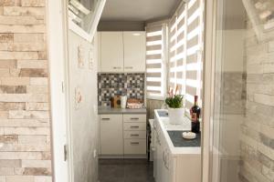 Elle comprend une petite cuisine avec des placards blancs et une fenêtre. dans l'établissement Apartman Hedonia, à Višegrad