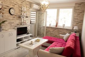 - un salon avec un canapé rouge et une télévision dans l'établissement Apartman Hedonia, à Višegrad