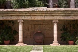 a stone wall with a large vase between two pillars at Atlantica Bay - Adults Only in Limassol